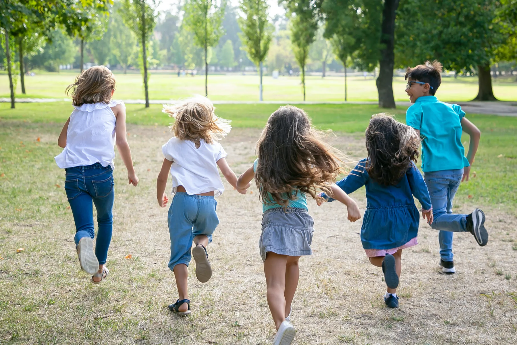Crianças a correr de mãos dadas num parque
