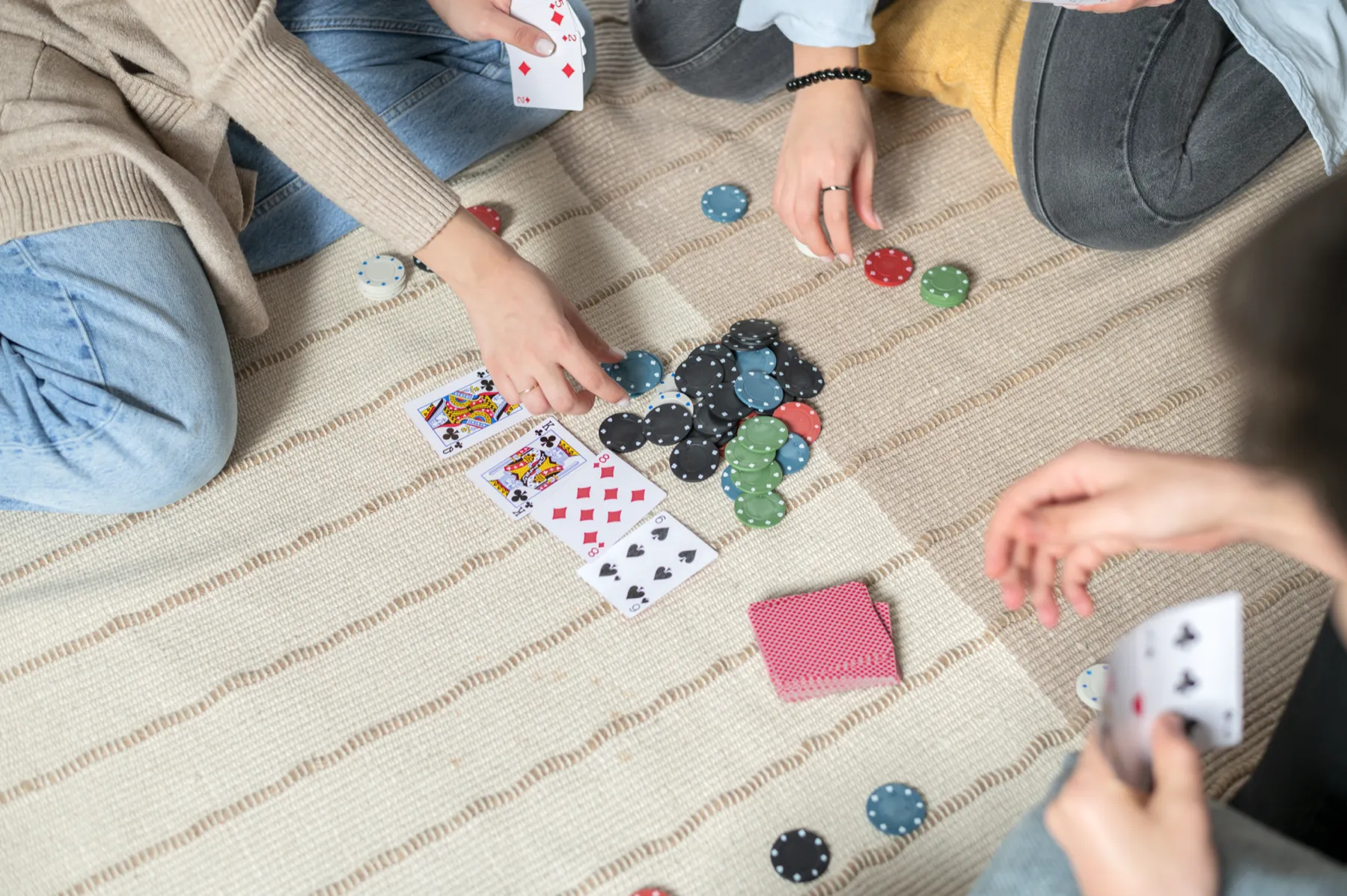 Mãos a jogar às cartas e fichas num tapete