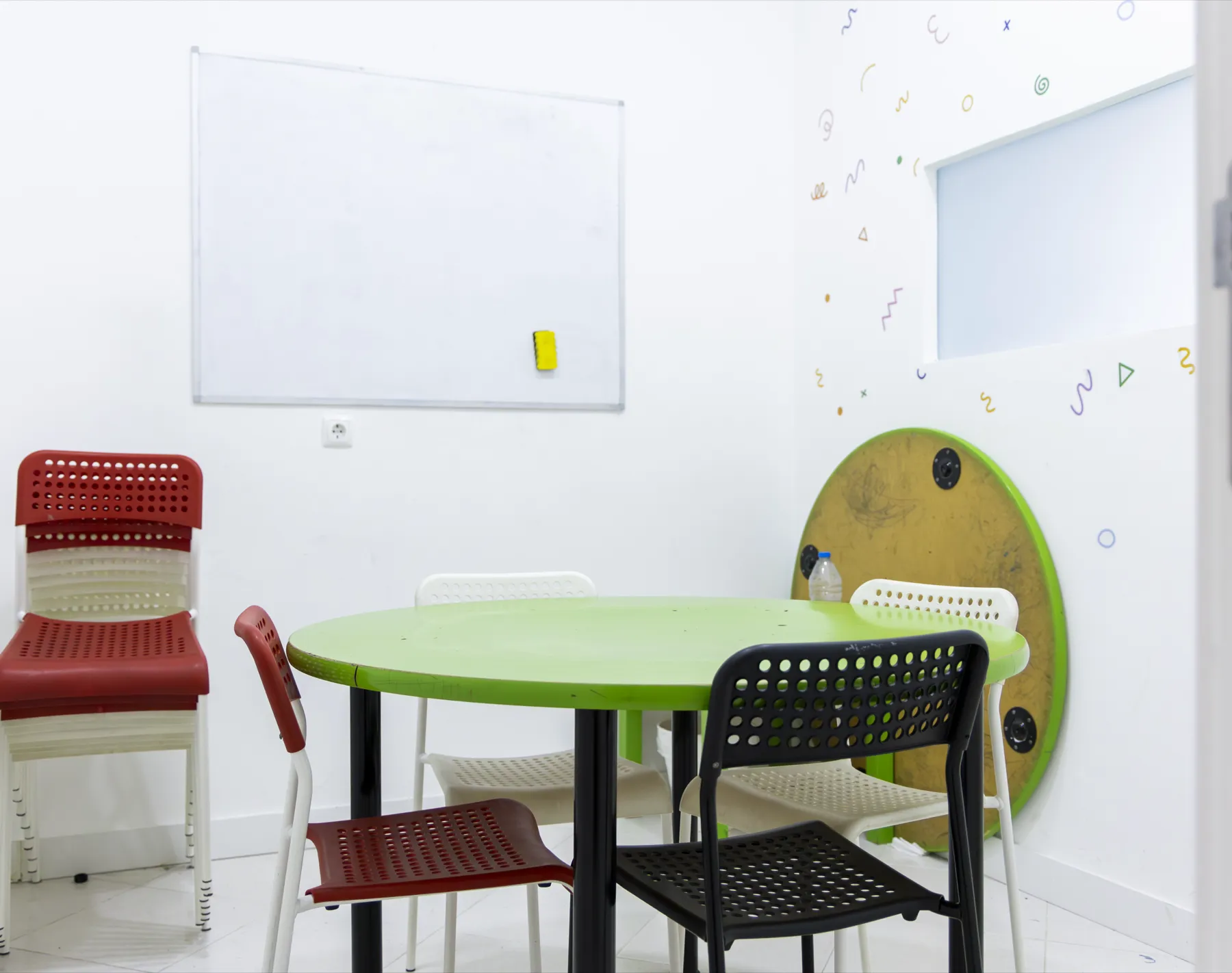 Sala de explicações com mesa redonda verde e quadro branco