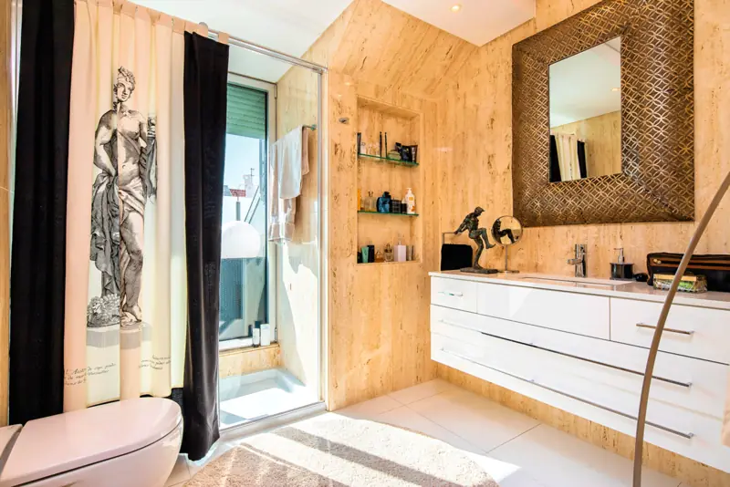 Timber lined bathroom with a woven frame mirror and a curtain printed with a classical statue