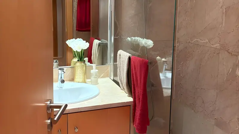 Blush marble washbasin with white tulips and a red towel