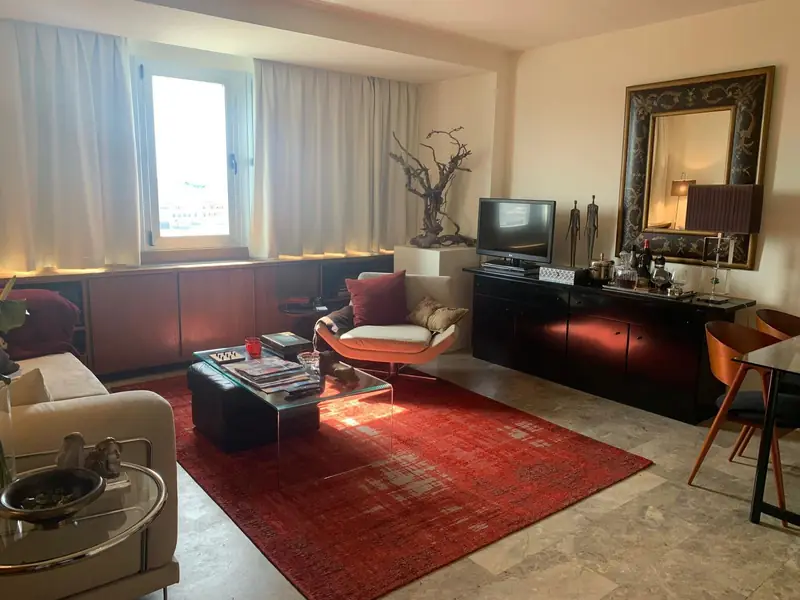 Sala com móveis lacados em vermelho escuro, espelho de moldura esculpida e tapete vermelho