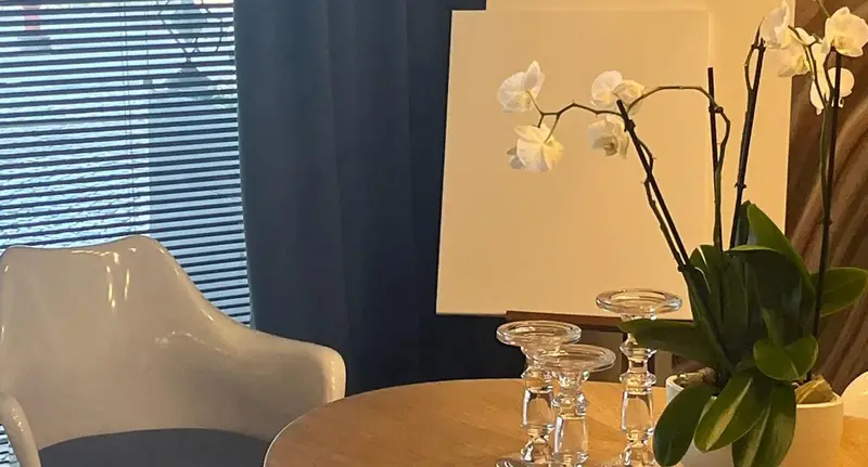 Orquídea branca e castiçais de vidro sobre mesa redonda de madeira
