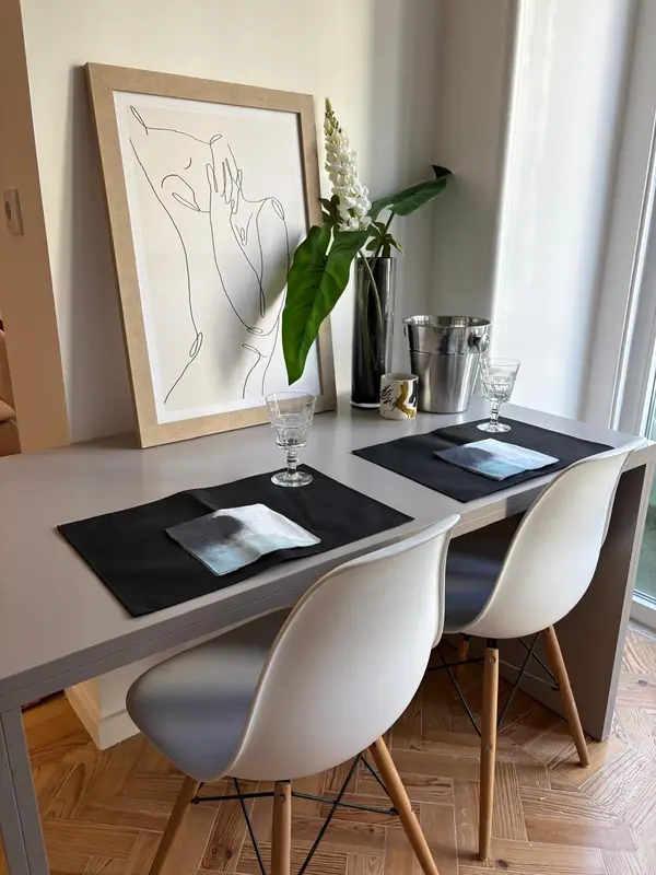 Mesa junto à janela com desenho a traço, balde de champanhe e cadeiras brancas