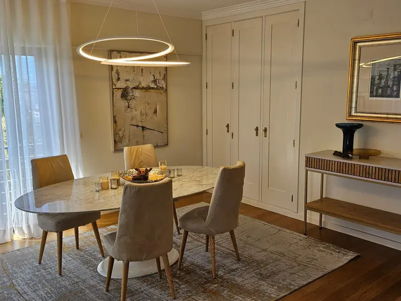 Sala de jantar com mesa oval de mármore, candeeiro de anéis e cadeiras de veludo