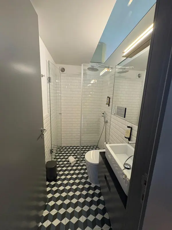 Casa de banho com chão de cubos em ilusão ótica, azulejo metro e duche de vidro
