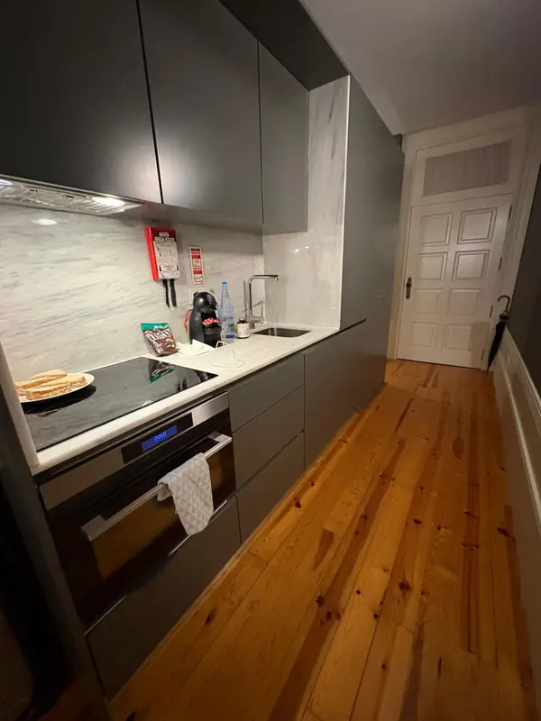 Cozinha linear em cinza-grafite com soalho de pinho e porta almofadada
