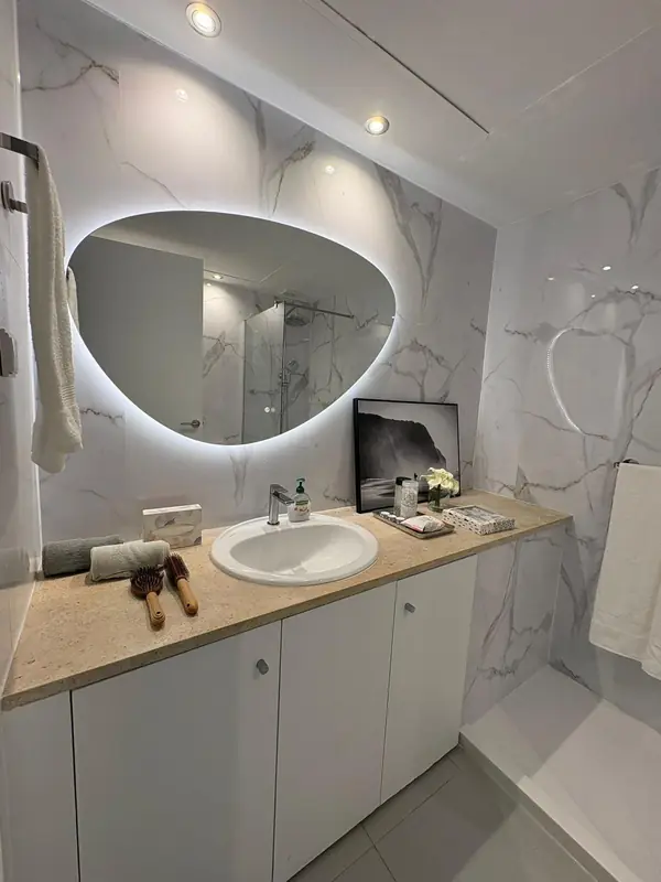 White marble bathroom with an organic backlit mirror