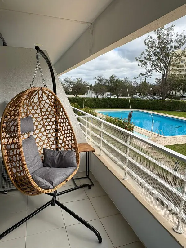 Cadeira suspensa de verga na varanda, sobre a piscina e o jardim