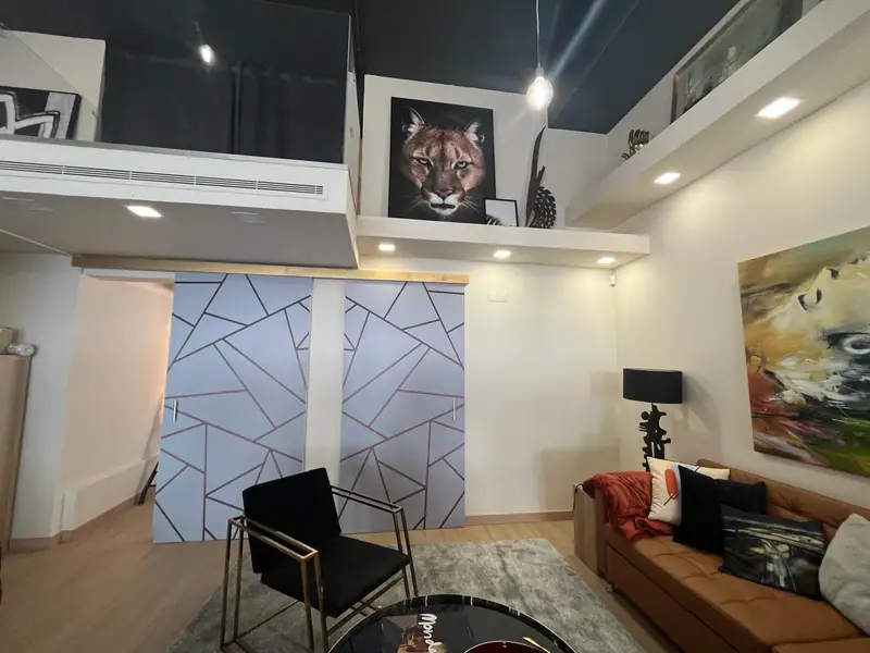 Loft com retrato de puma no mezanino, portas de desenho geométrico e sofá caramelo