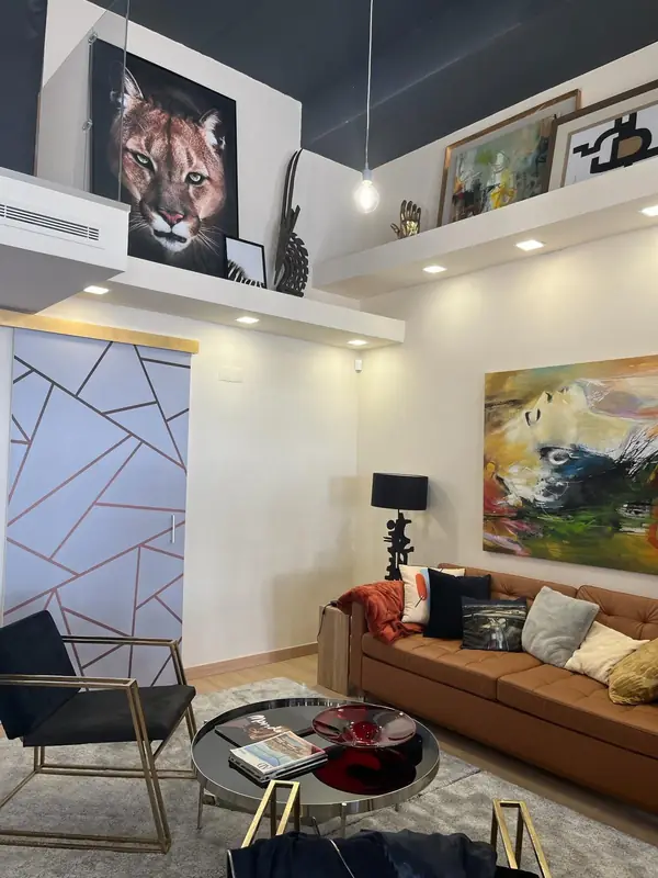 Vista vertical do loft com teto escuro, cadeira negra e pintura abstrata