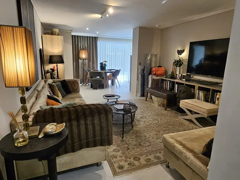 Sala longa com sofá de pelo, tapete clássico e candeeiros de tecido plissado