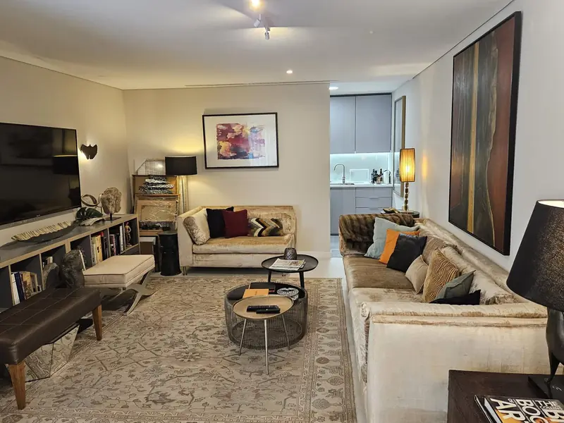 Sala com estantes baixas, sofá capitonê e pintura de grande formato