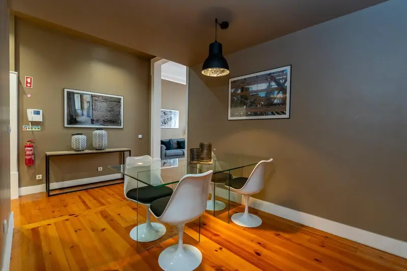Dining area with a glass table, white tulip chairs and an industrial pendant