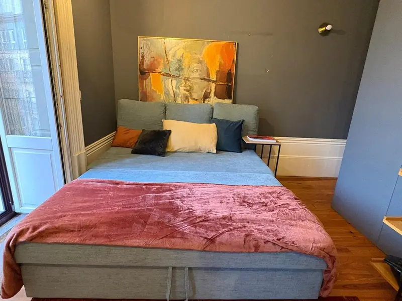 Quarto com parede verde-azeitona, pintura laranja e colcha cor de framboesa