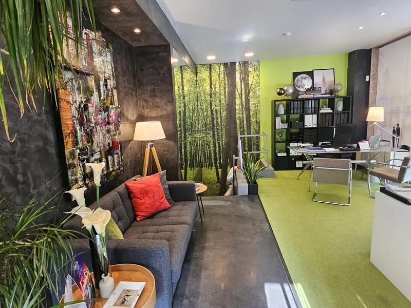 Entrada de escritório com parede de colagens, arranjo de copos-de-leite e mural de floresta