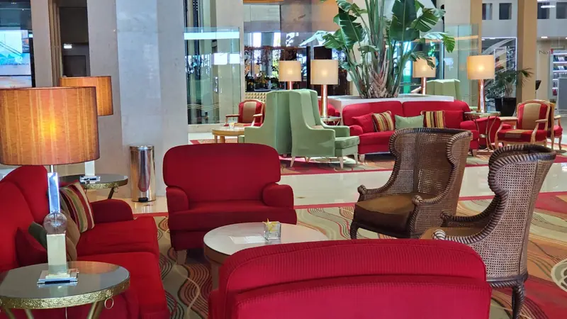 Lounge com cadeirões vermelhos, poltronas de verga e candeeiros de pé