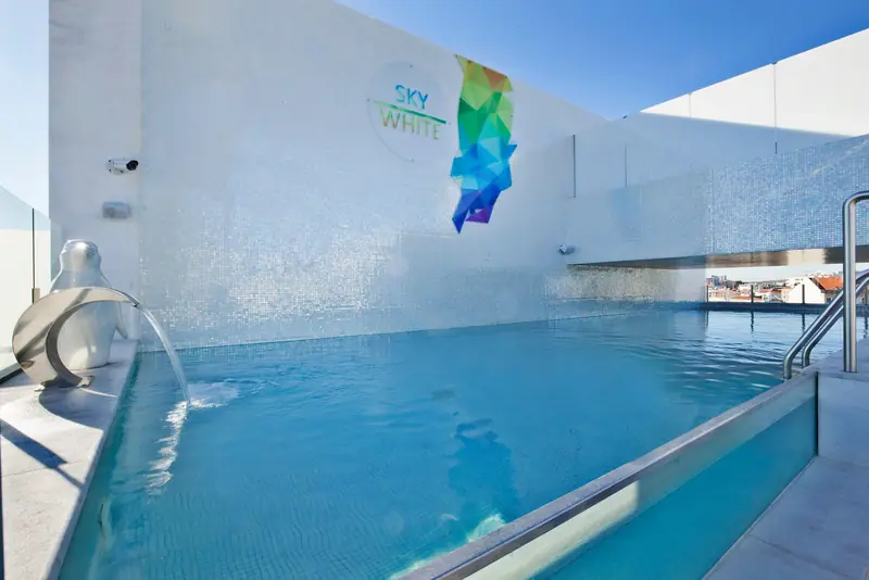 Piscina de cobertura com borda de vidro e parede branca com arte geométrica