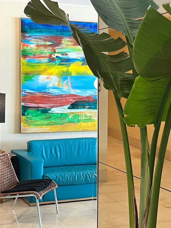 Poltrona azul-turquesa junto a uma estrelícia e uma pintura de cores vivas