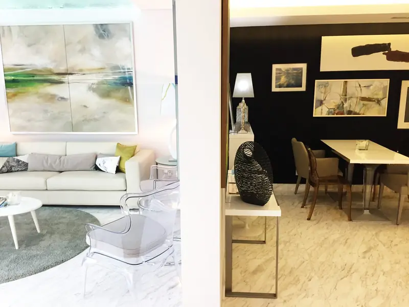 Espaço comum com sofá branco, pintura de paisagem e zona de mesas junto a parede negra