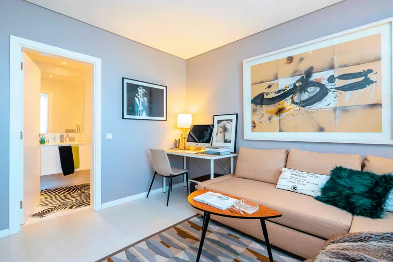 Sala e escritório com sofá cor de pêssego, pintura caligráfica e almofada verde-esmeralda
