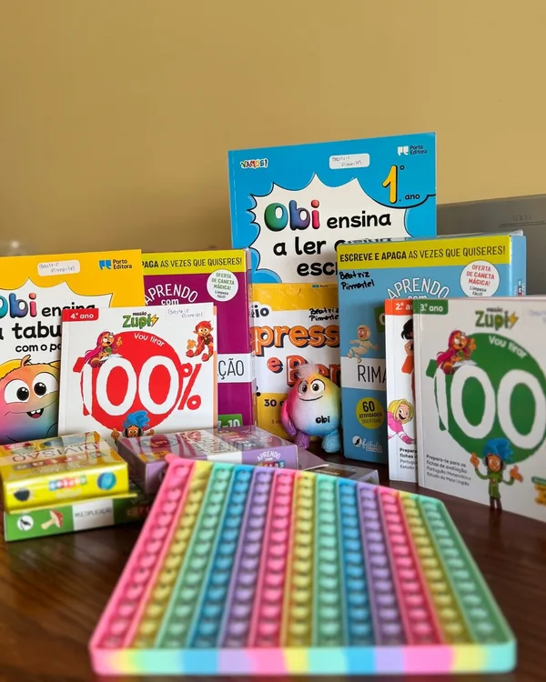 Livros de atividades e um tapete sensorial colorido em cima de uma mesa.