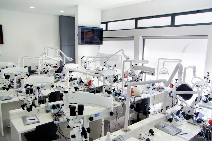 Laboratório com filas de postos de trabalho, microscópios e simuladores