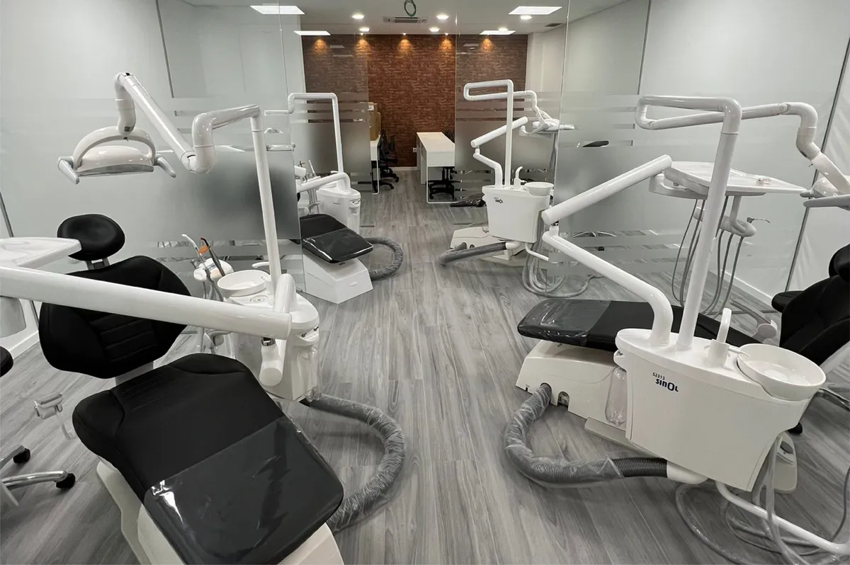 Sala clínica com cadeiras de medicina dentária e parede de tijolo ao fundo